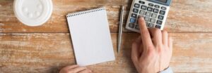 Main tenant une fiche de paie avec une calculatrice sur un bureau