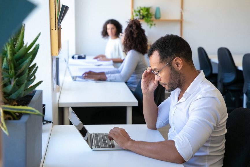 Main tenant une calculatrice sur un bureau encombré de dossiers