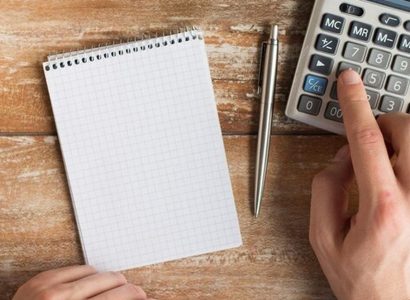 Main tenant une fiche de paie avec une calculatrice sur un bureau