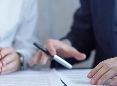 Deux professionnels analysant un contrat avec une loupe sur une clause d'indexation